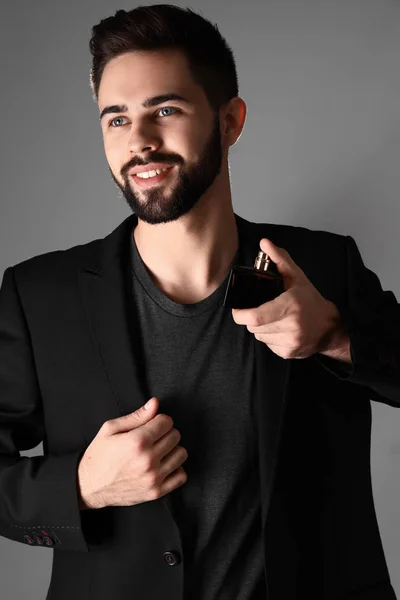 Hombre guapo con botella de perfume sobre fondo gris —  Fotos de Stock