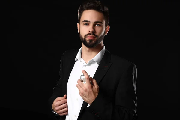 Hombre guapo con botella de perfume sobre fondo oscuro —  Fotos de Stock