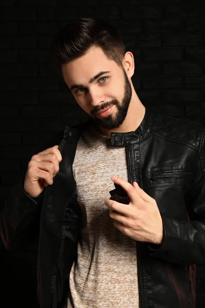 Handsome man with bottle of perfume on dark background — Stock Photo, Image