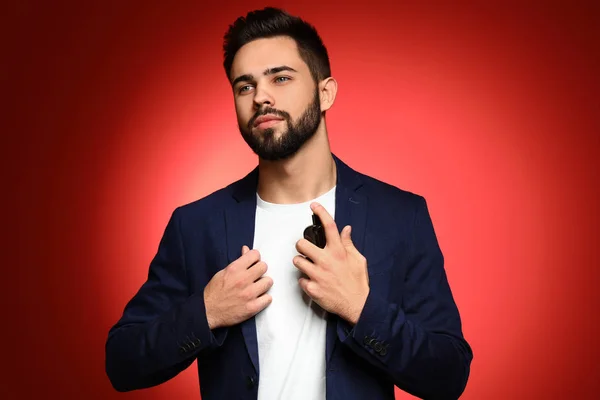 Handsome man with bottle of perfume on color background — Stock Photo, Image