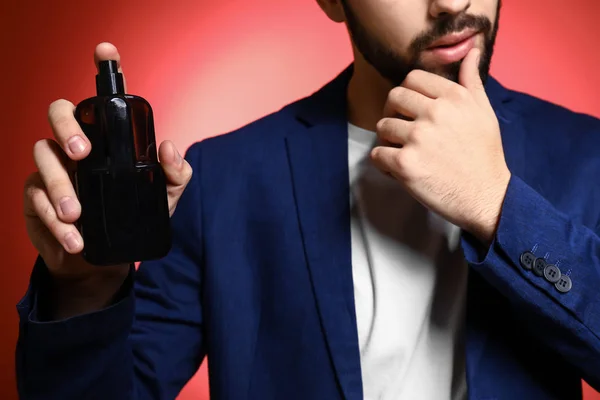 Handsome man with bottle of perfume on color background, closeup — Stock Photo, Image