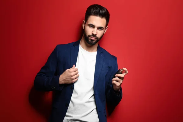 Handsome man with bottle of perfume on color background — Stock Photo, Image