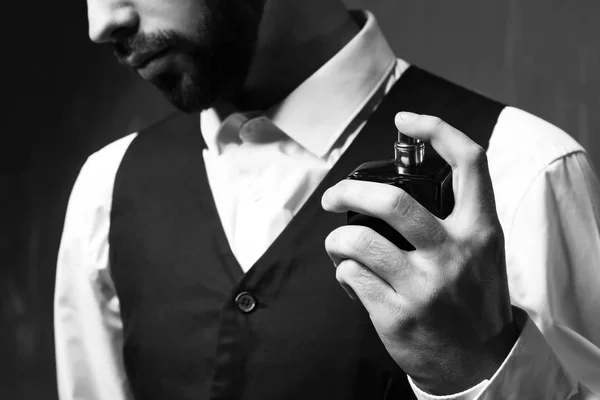 Handsome man with bottle of perfume on grey background, closeup — Stock Photo, Image