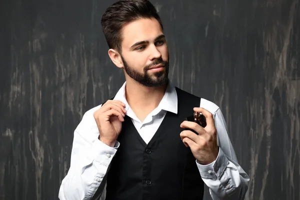 Hombre guapo con botella de perfume sobre fondo gris —  Fotos de Stock