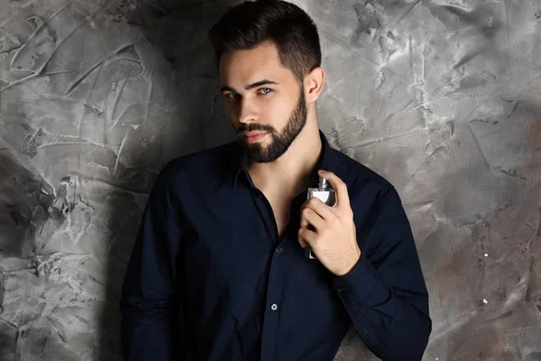 Hombre guapo con botella de perfume sobre fondo gris —  Fotos de Stock