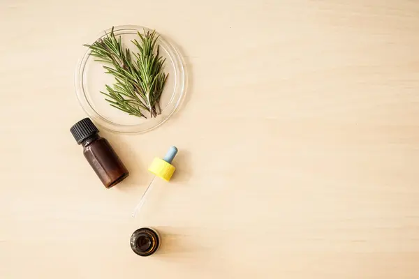 Botellas de aceite y romero fresco sobre mesa de madera —  Fotos de Stock
