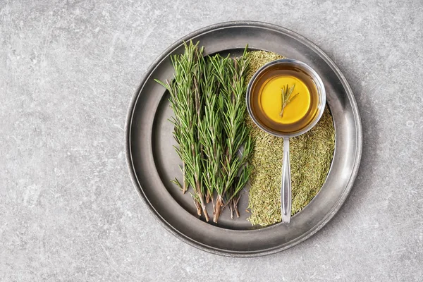 Tray with fresh and dry rosemary and oil on grey table — Stock Photo, Image