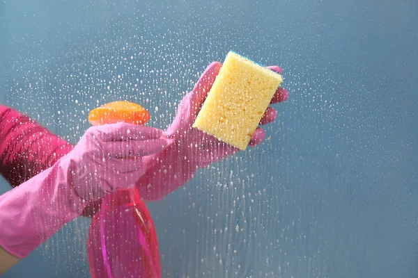 Vrouw wassen venster met afwasmiddel — Stockfoto