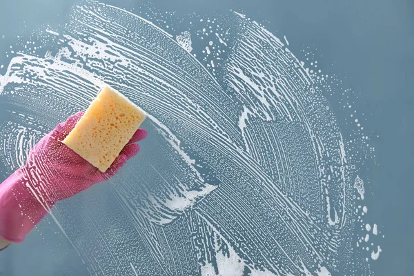 Woman washing window with detergent