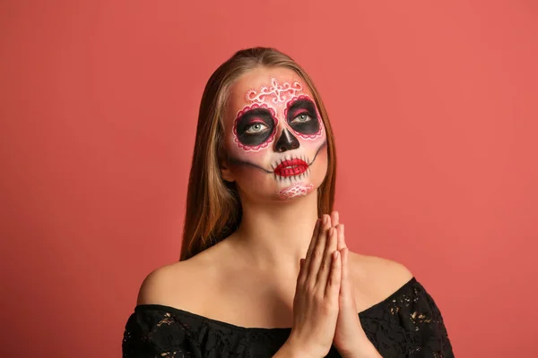 Young woman with painted skull on her face for Mexico's Day of the Dead against color background — Stock Photo, Image