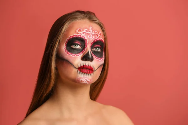 Jonge vrouw met geschilderde schedel op haar gezicht voor Mexico 's Dag van de Doden tegen kleur achtergrond — Stockfoto