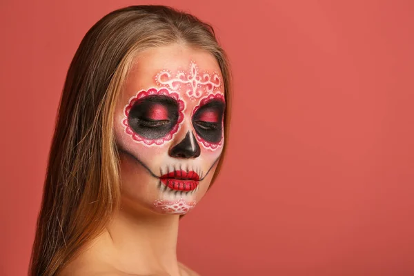 Young woman with painted skull on her face for Mexico's Day of the Dead against color background — Stock Photo, Image