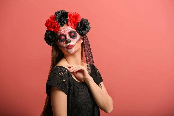 Young woman with painted skull on her face for Mexico's Day of the Dead against color background — Stock Photo, Image