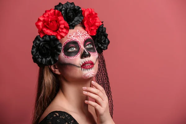 Young woman with painted skull on her face for Mexico's Day of the Dead against color background — Stock Photo, Image