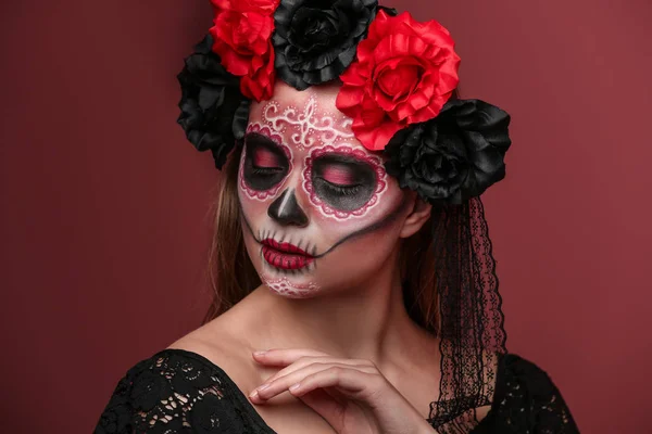 Young woman with painted skull on her face for Mexico's Day of the Dead against color background — Stock Photo, Image