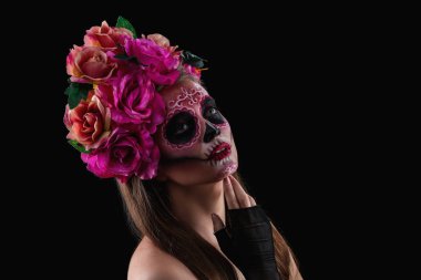 Yüzünde koyu arka plan karşı ölülerin Meksika'nın günü için boyalı kafatası ile genç kadın