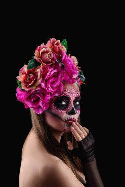Yüzünde koyu arka plan karşı ölülerin Meksika'nın günü için boyalı kafatası ile genç kadın