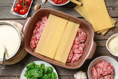 Ahşap masada kıyılmış et, lazanya levhalar ve malzemeler ile güveç