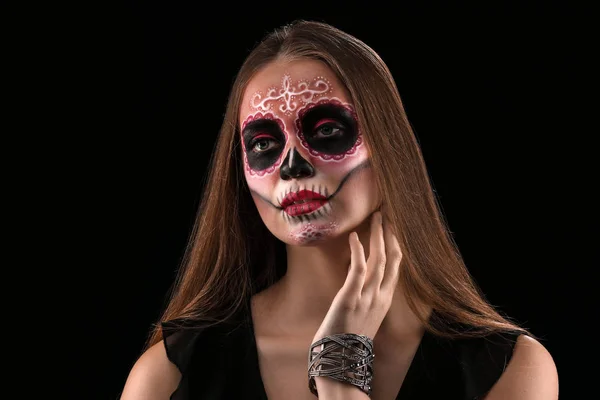 Young woman with painted skull on her face for Mexico's Day of the Dead against dark background — Stock Photo, Image