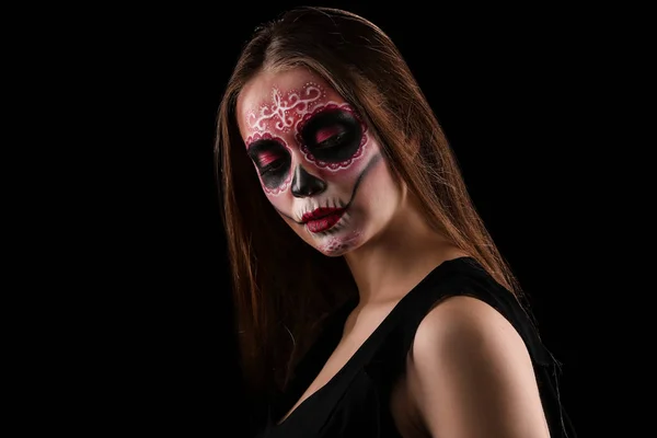 Young woman with painted skull on her face for Mexico's Day of the Dead against dark background — Stock Photo, Image