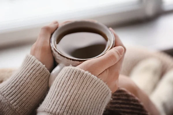 Mladá žena pít horký čaj doma, closeup — Stock fotografie