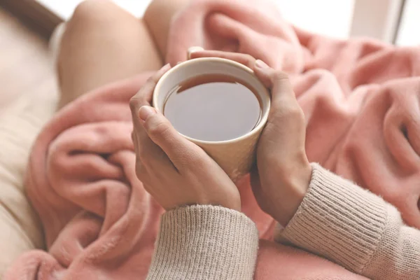 Mladá žena pít horký čaj doma — Stock fotografie