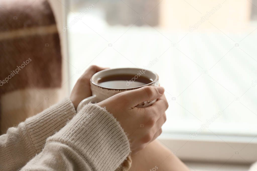 Young woman drinking hot tea at home, closeup