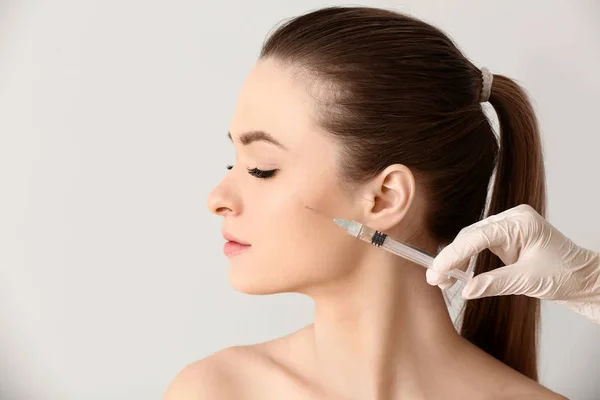 Young woman receiving injection in face on light background — Stock Photo, Image