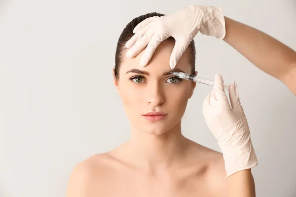 Young woman receiving injection in face on light background — Stock Photo, Image