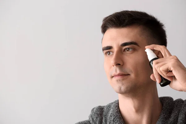 Handsome man with face serum on light background — Stock Photo, Image