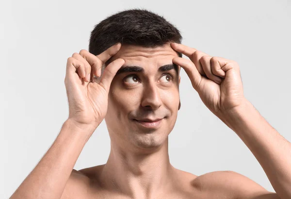 Hombre dándose masaje facial sobre fondo claro — Foto de Stock