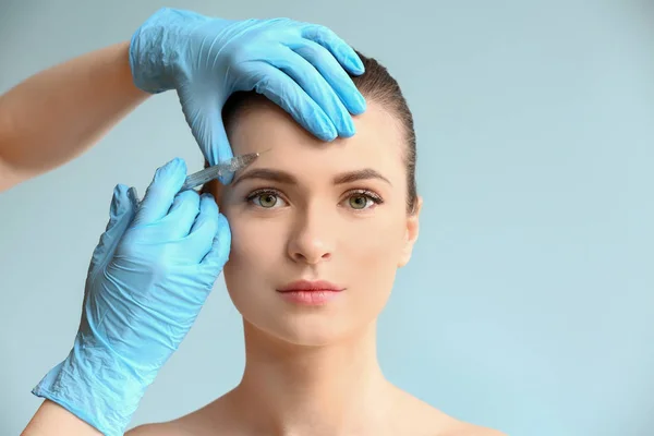 Jovem mulher recebendo injeção no rosto sobre fundo de cor — Fotografia de Stock