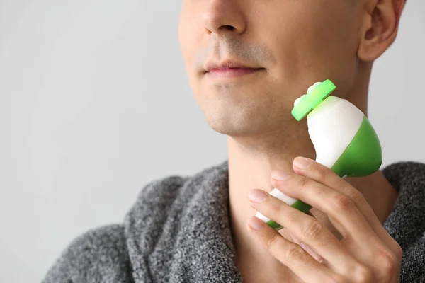 Man with facial massage tool on light background, closeup — Stock Photo, Image