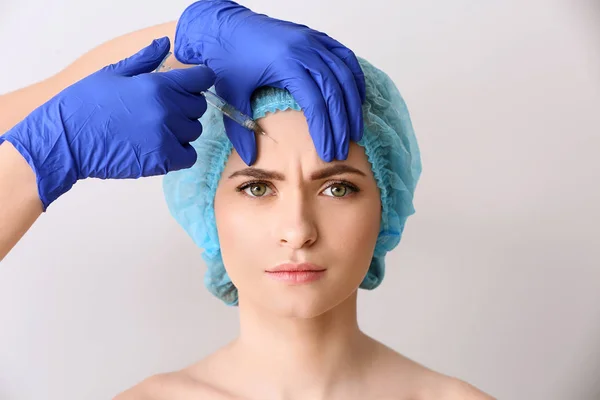 Jovem mulher a receber injeção no rosto sobre fundo claro — Fotografia de Stock