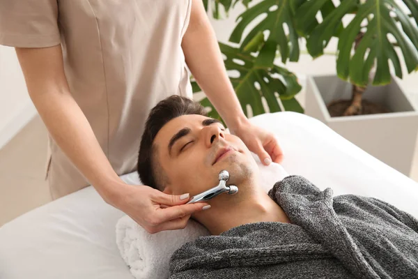 Mężczyzna odbiera masaż twarzy w gabinecie kosmetycznym — Zdjęcie stockowe