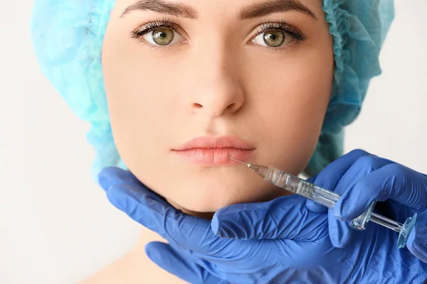 Junge Frau bekommt vor hellem Hintergrund Injektion ins Gesicht — Stockfoto