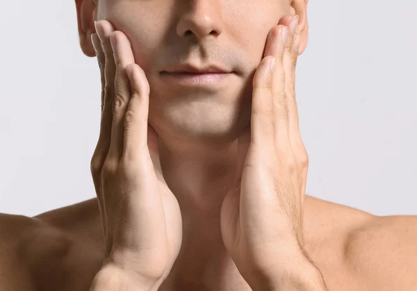Man die zichzelf gezicht massage geeft op lichte achtergrond — Stockfoto