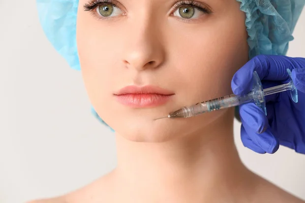 Junge Frau erhält Injektion ins Gesicht auf hellem Hintergrund, Nahaufnahme — Stockfoto