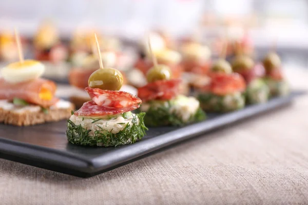 Placa con sabrosos canapés en la mesa — Foto de Stock