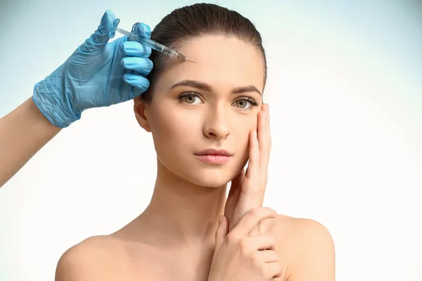 Young woman receiving injection in face on color background — Stock Photo, Image