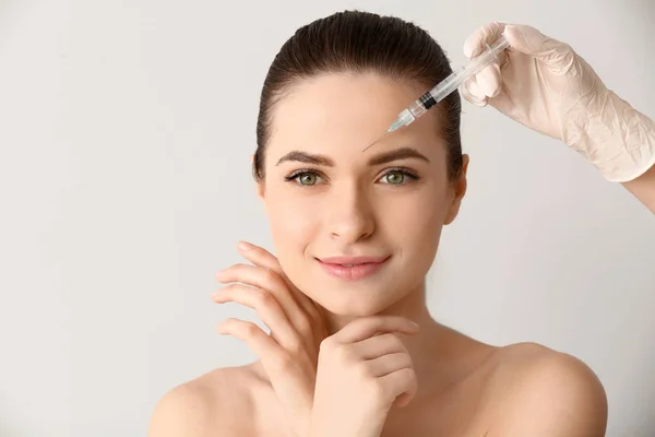 Jovem mulher a receber injeção no rosto sobre fundo claro — Fotografia de Stock