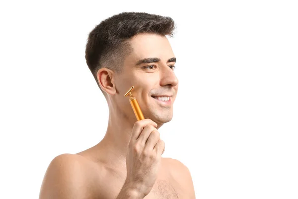 Homem com ferramenta de massagem facial em fundo branco — Fotografia de Stock