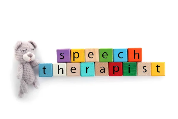 Cubes with text SPEECH THERAPIST and toy on white background — Stock Photo, Image