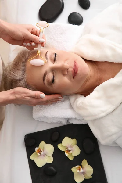 Mature woman receiving face massage in beauty salon — Stock Photo, Image