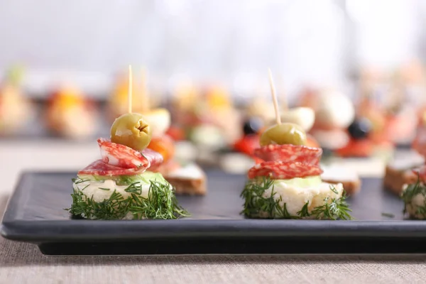 Placa com canapés saborosos na mesa — Fotografia de Stock