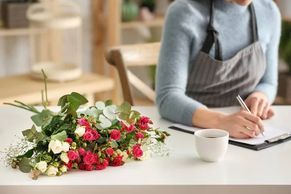 Linda florista feminina trabalhando à mesa na loja — Fotografia de Stock