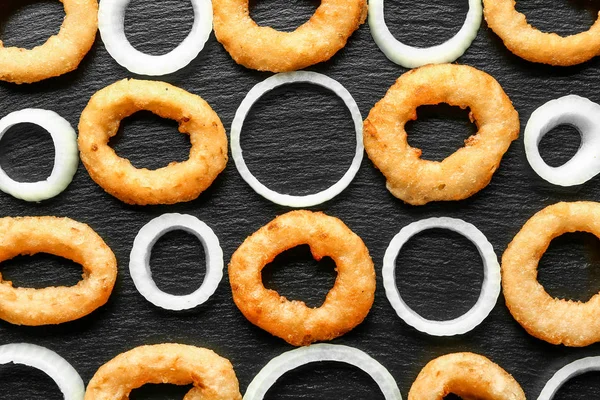 Raw and fried onion rings on dark background — Stock Photo, Image