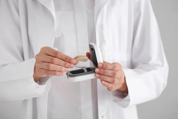 Médica com aparelho auditivo e caixa, close-up — Fotografia de Stock