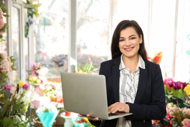 Güzel kadın sahibi çiçekçi dükkanı içinde laptop ile