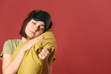 Maske ve yastık renk arka plan üzerinde uykulu genç kadınla